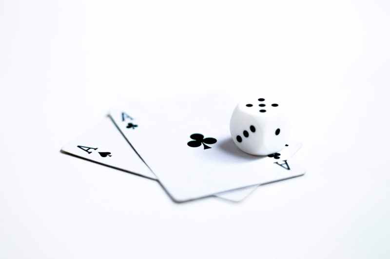 white and black dice on two ace of clubs and spades cards